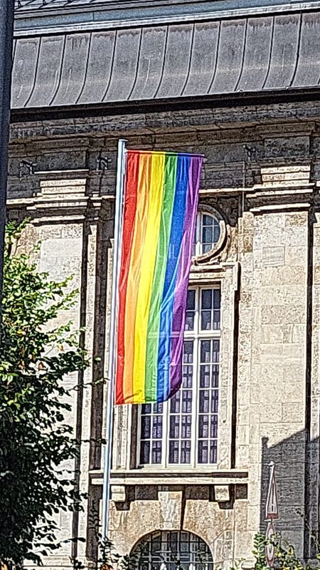 Regenbogenfahne hängt an der Fassade eines Darmstädter Gebäudes an der Demostrecke